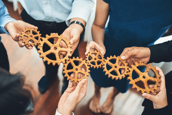 image shows business coaching visualization using wheel cogs held by individuals who need business coaching.